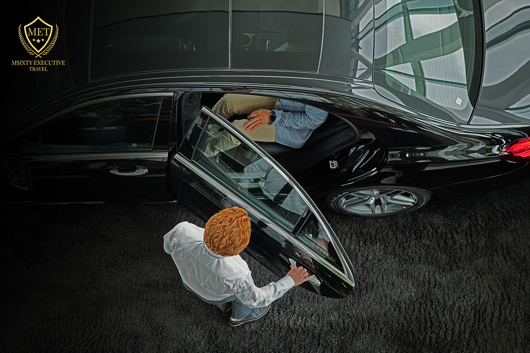 a chauffeur opening the door of a luxury premium car for the passenger shot from above