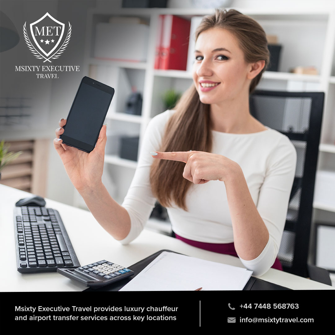 A lady holding a phone in front of a computer ready to assist a client of a chauffeur company in Birmingham